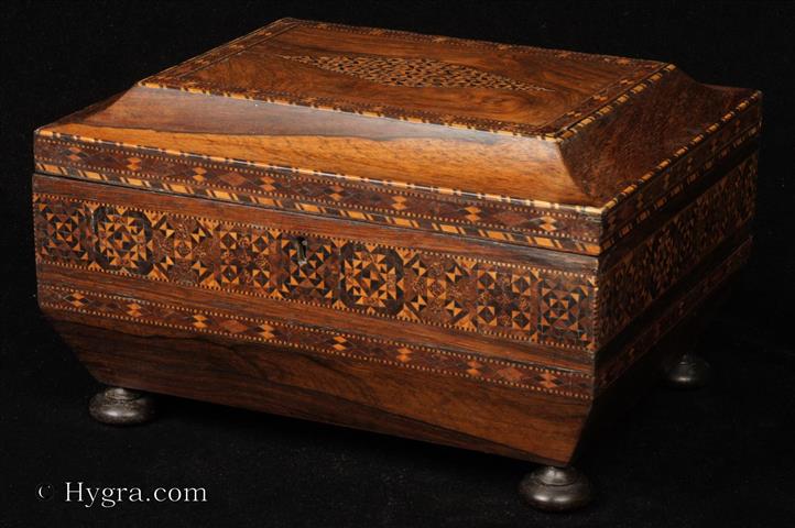 Rosewood Tunbridge ware box of Egyptian inspired sarcophagus form, the lid with a cavetto molding. The sides and top are inlaid with parquetry   created by the stickware method. The inside of the box which has a lift-out tray has been relined with velvet and hand made paper making the box ideal for jewelry. The box stands  on turned solid rosewood feet. Circa 1820.  Enlarge Picture